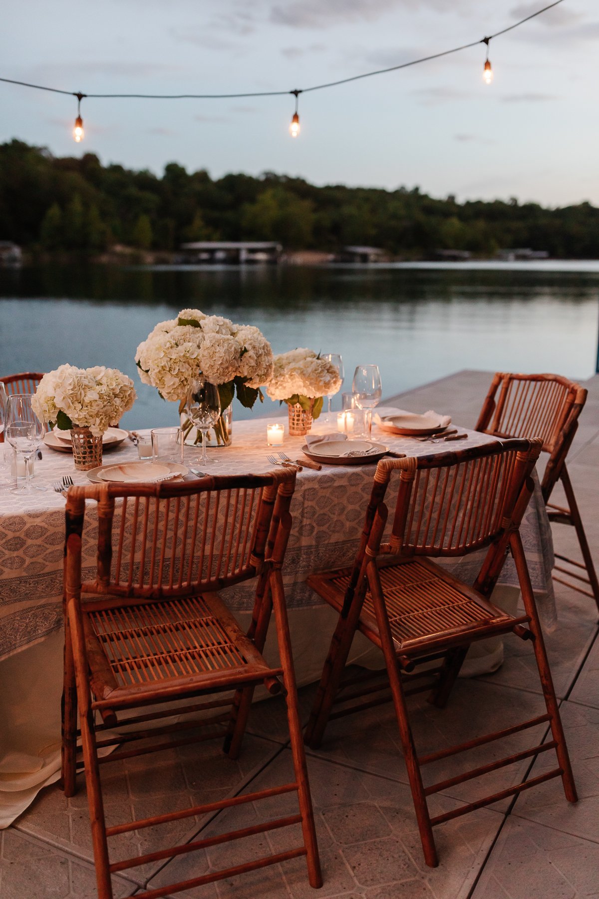 A blue and white table cloth set with bamboo plates and an al fresco dining view of the water
