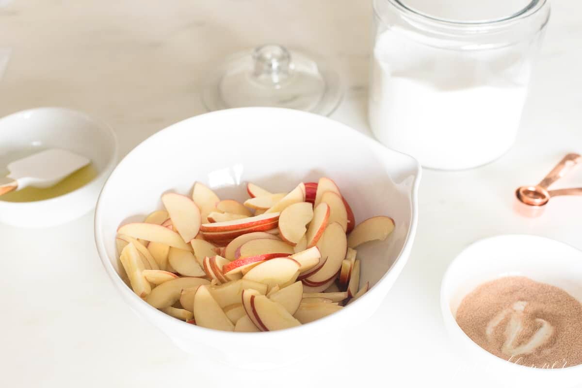 Baked apple slices in a bowl next to other ingredients.