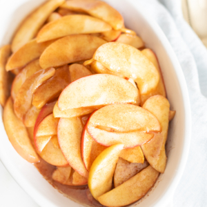 Baked apple slices arranged in a white dish with a spoon.