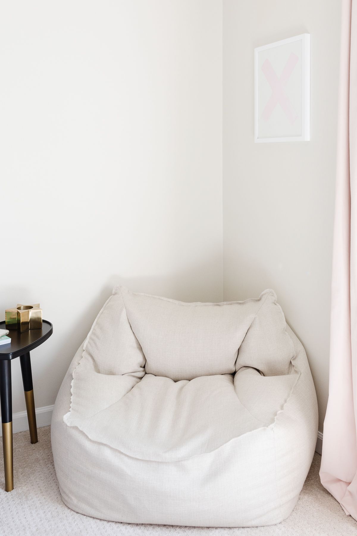 A neutral bean bag chair in the corner of a cream tween bedroom.