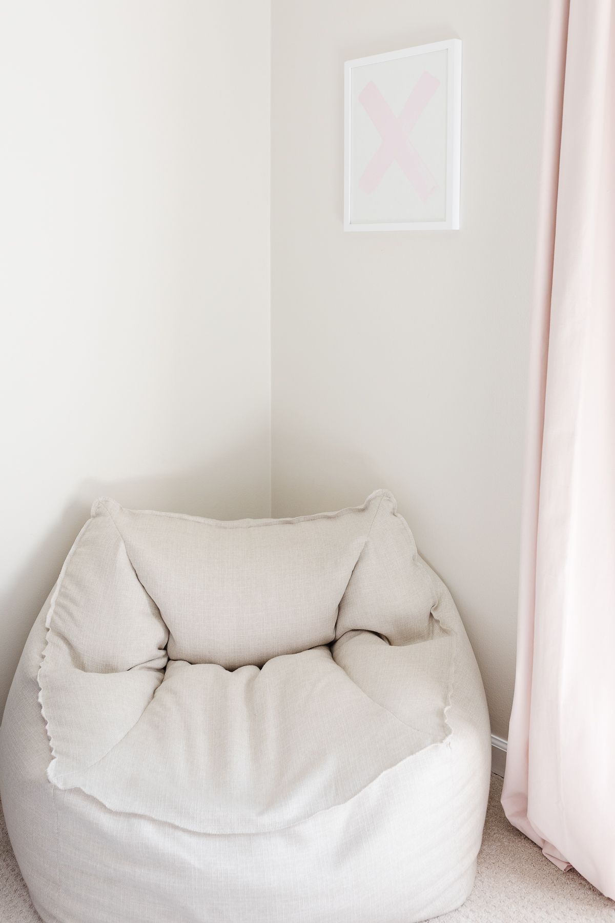 A neutral bean bag chair in the corner of a cream tween bedroom.