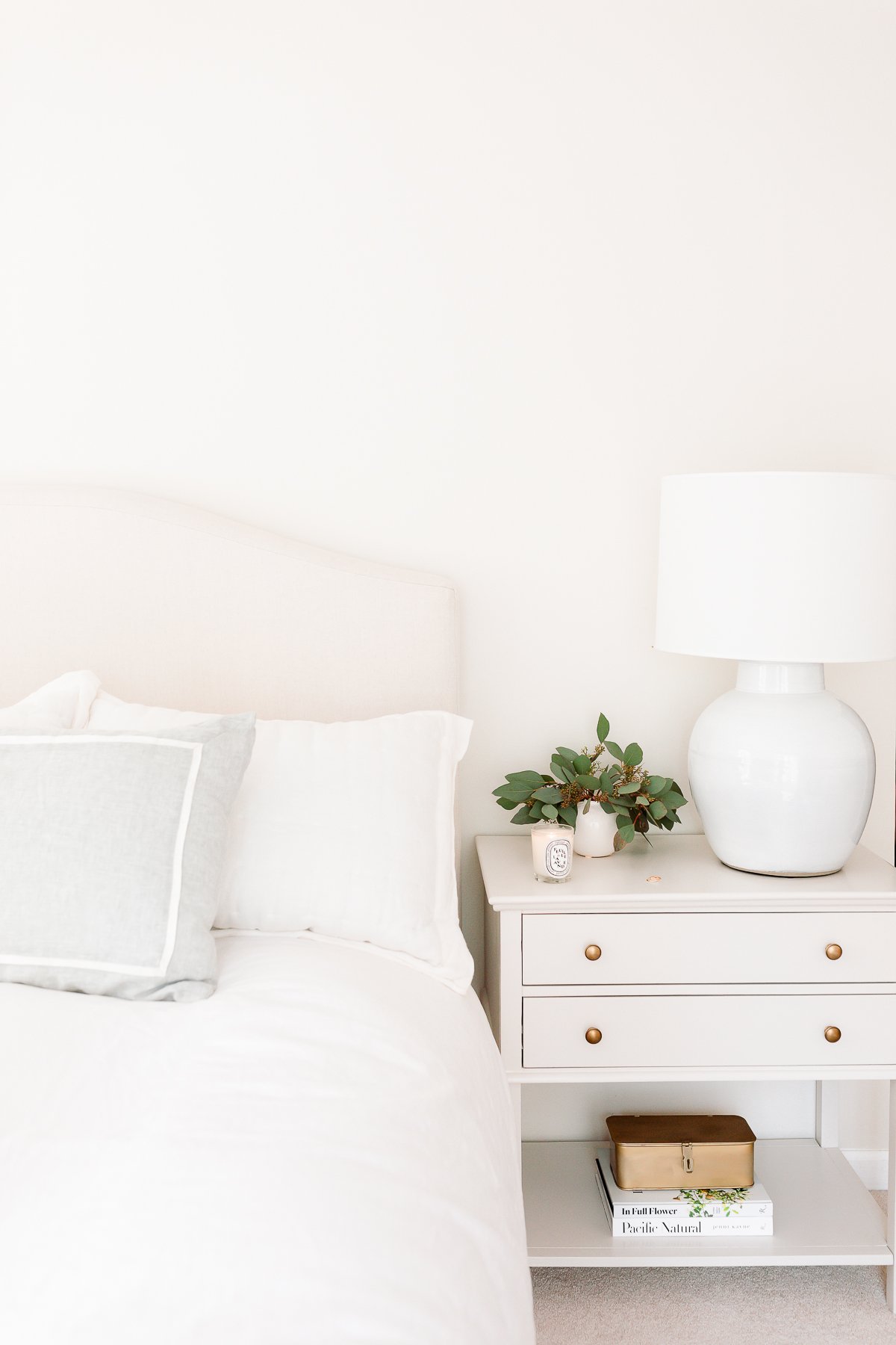 neutral bed and neutral nightstand at approximately the same bedside table height.