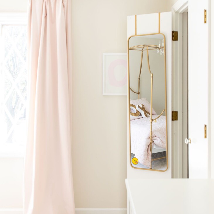 A girl's bedroom with pink blackout curtains and a mirror hanging on a closet door.