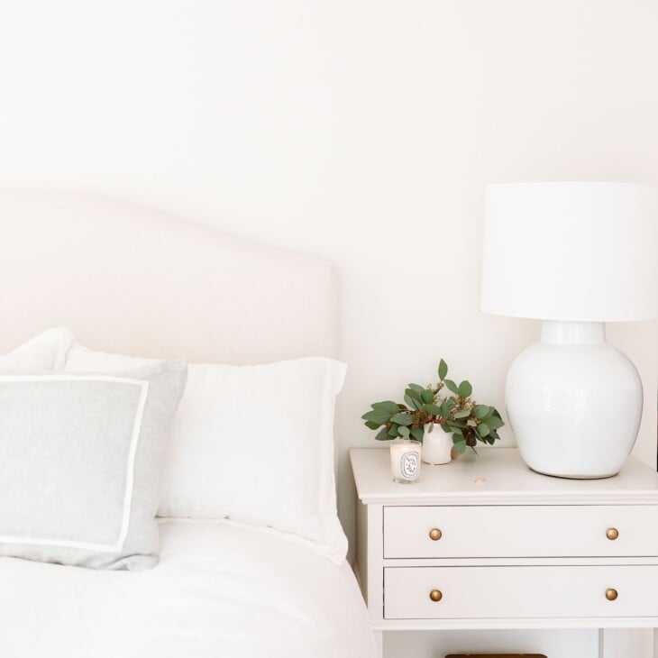 A cream bedroom with cream bed and greige nightstand