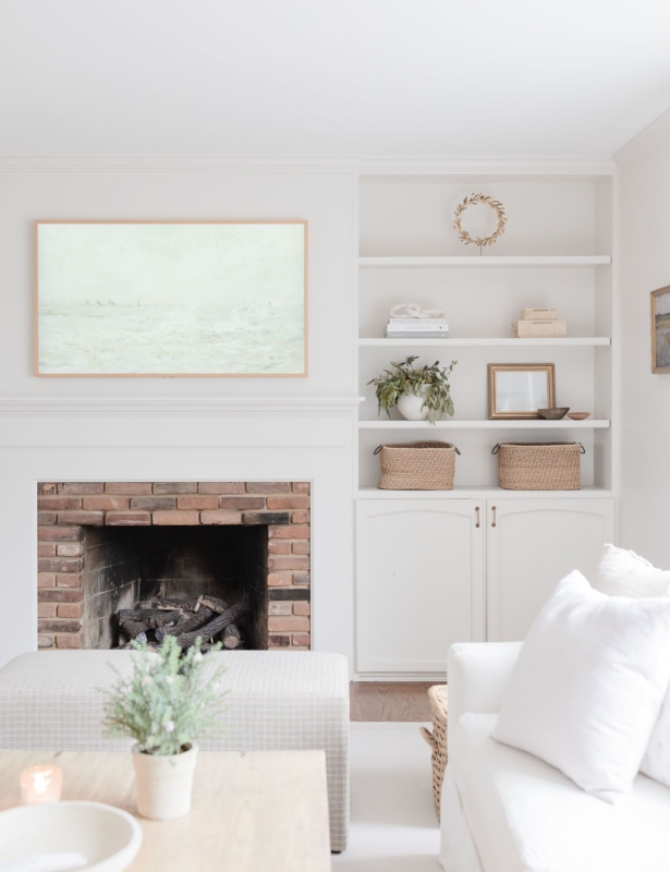 A white living room with built in bookshelves around a brick fireplace.