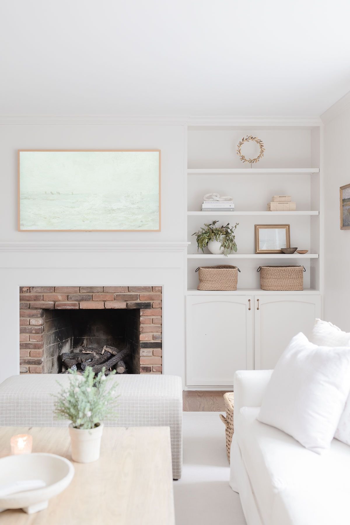 A white living room with built in bookshelves around a brick fireplace.