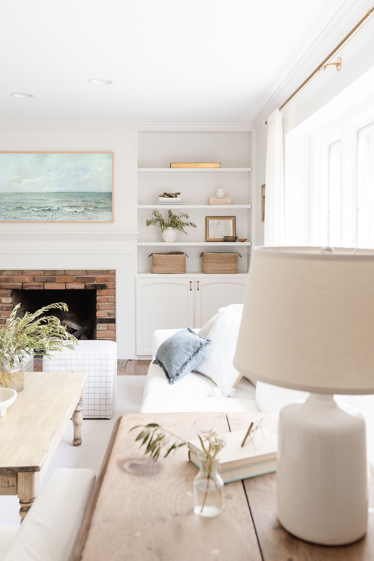 A white living room with built in bookshelves around a brick fireplace.