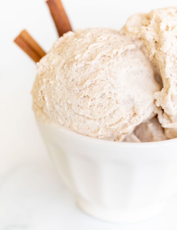 A white bowl full of homemade cinnamon ice cream with a cinnamon stick as garnish on the side