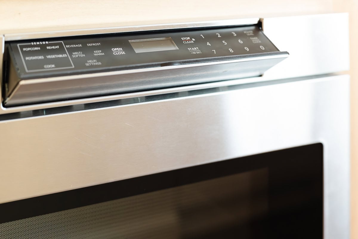 Close-up of a stainless steel oven with a digital control panel and keypad located above the door, complemented by a sleek under counter microwave drawer for modern kitchen convenience.