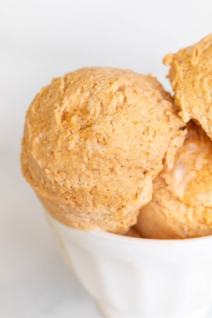 A white bowl of pumpkin ice cream on a marble surface.