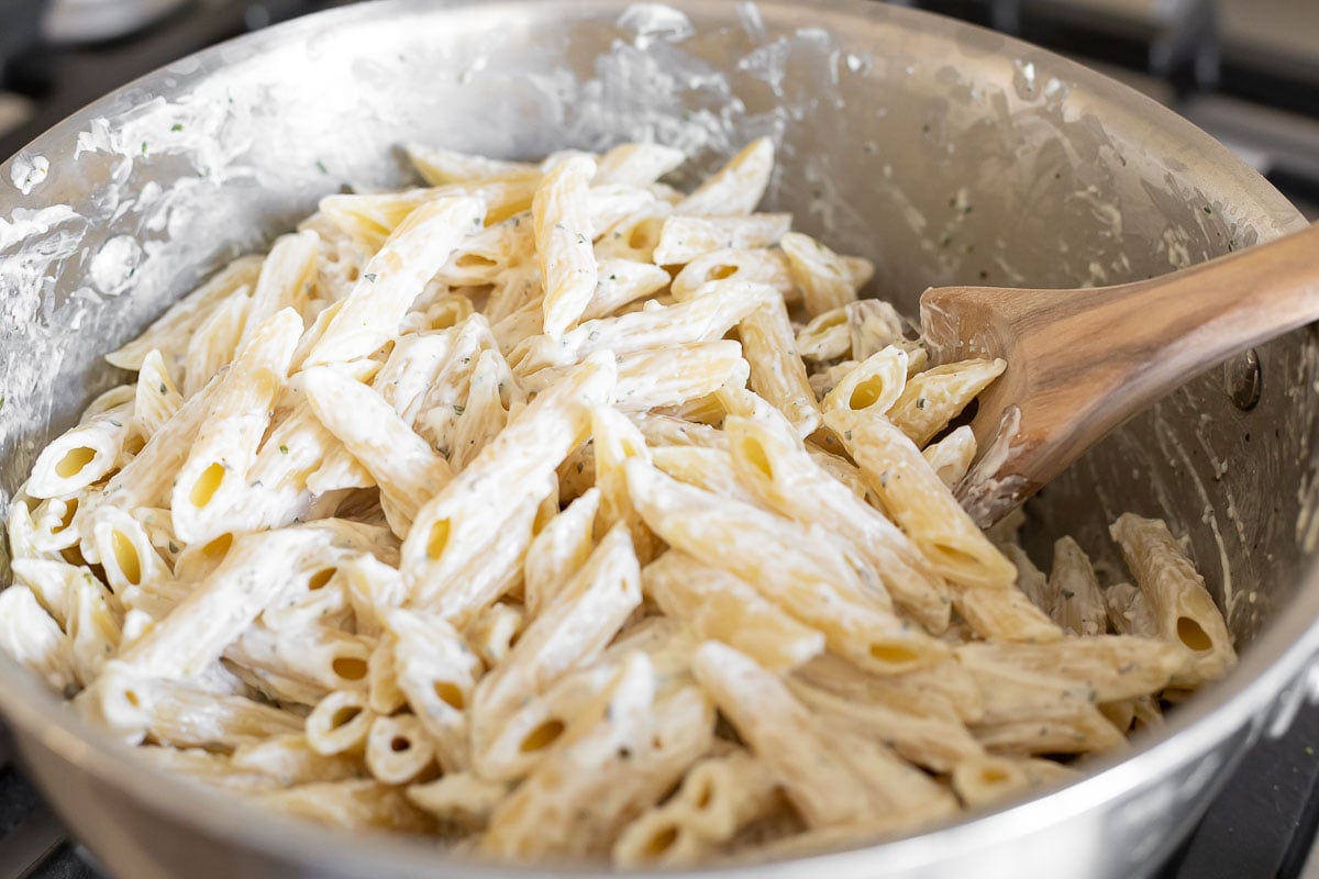Boursin pasta in a stainless steel pan on a stovetop.