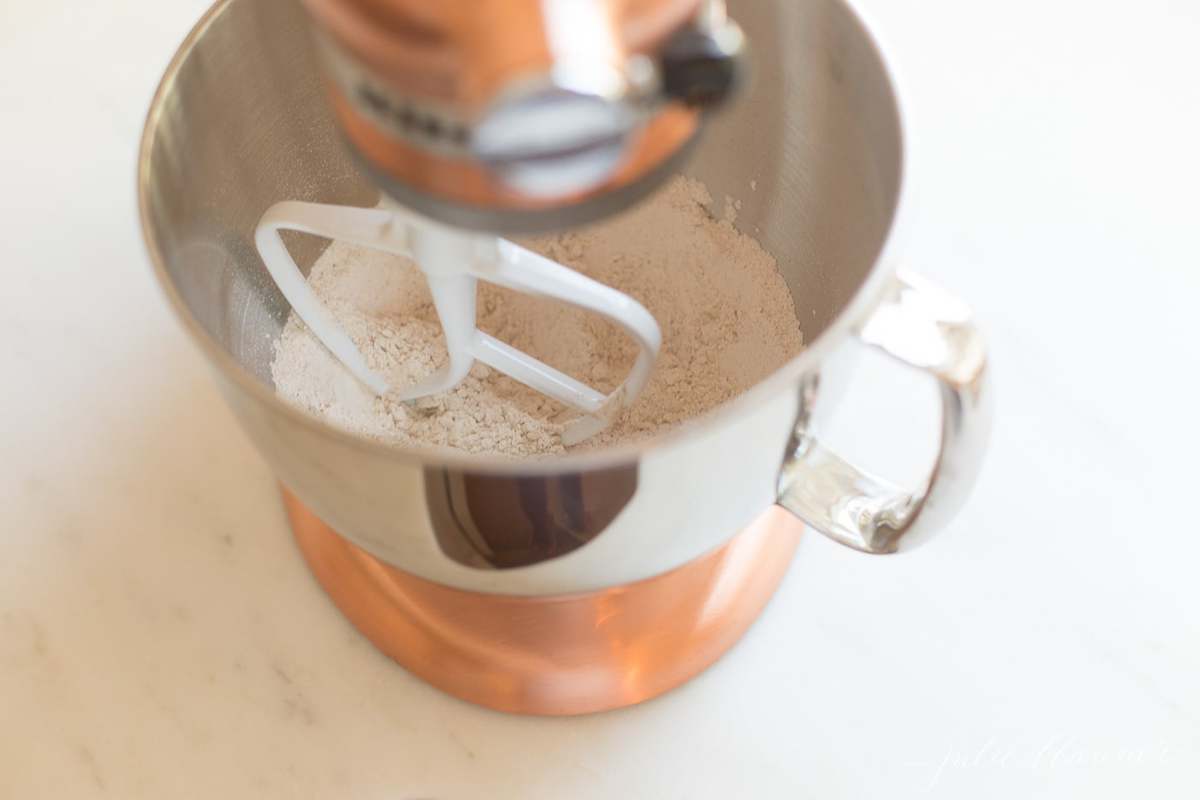a copper mixer with muffin recipe ingredients inside the bowl.