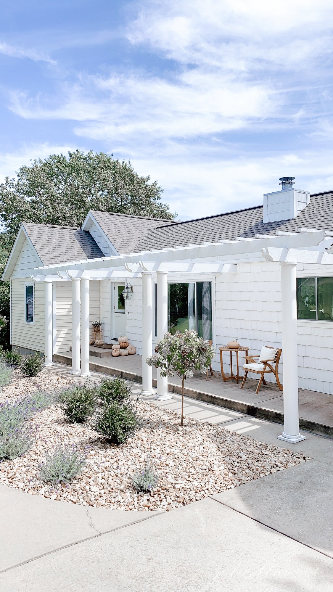 A white cottage with an attached front porch pergola