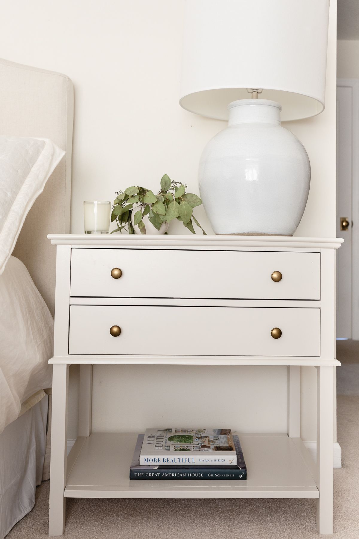 A nightstand in a cream bedroom, painted in a greige paint color.