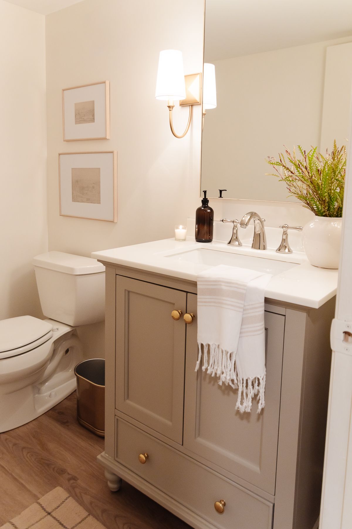 A bathroom in basement with gold sconces and a gray vanity