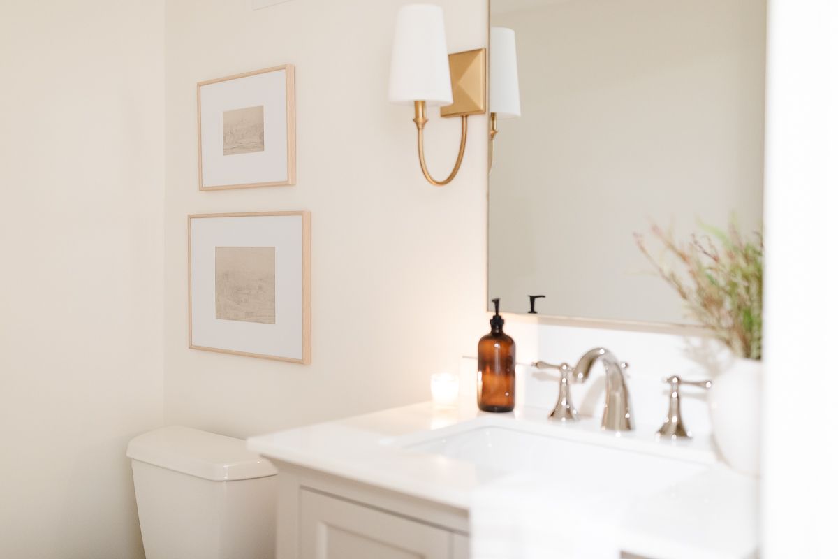 A bathroom in basement with gold sconces and a gray vanity
