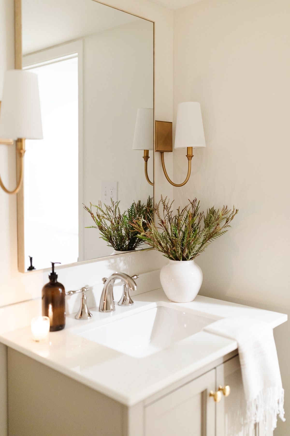 A bathroom in basement with gold sconces and a gray vanity