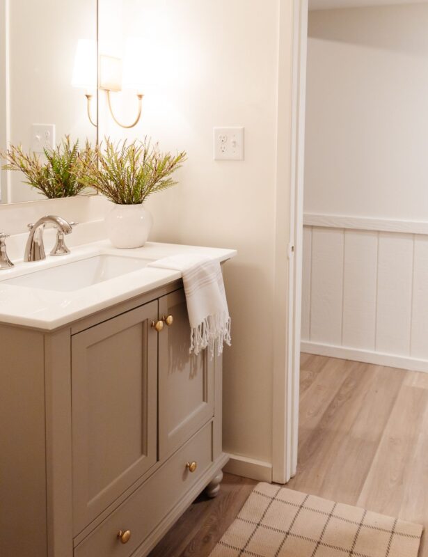 A small bathroom with gold sconces, greige vanity and walls painted Cloud White