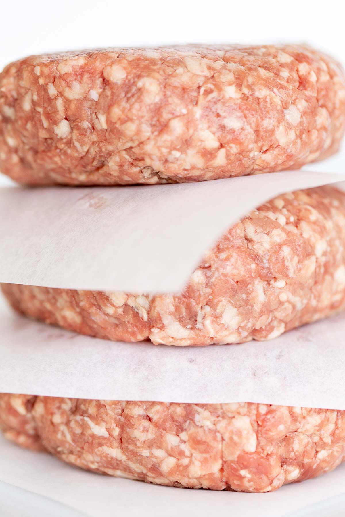 a stack of burger patties with parchment paper in between layers