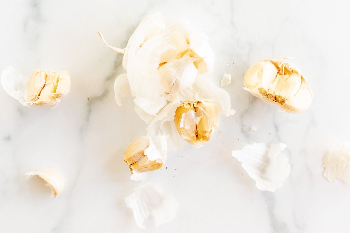 A bulb of garlic laid out in cloves on a marble surface