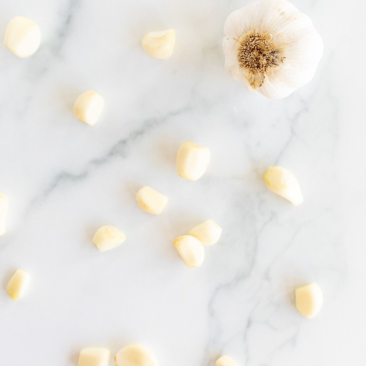 Garlic cloves laid out on a marble surface.