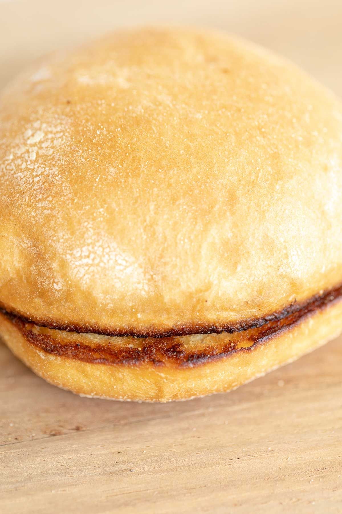 A toasted burger bun on a wooden cutting board