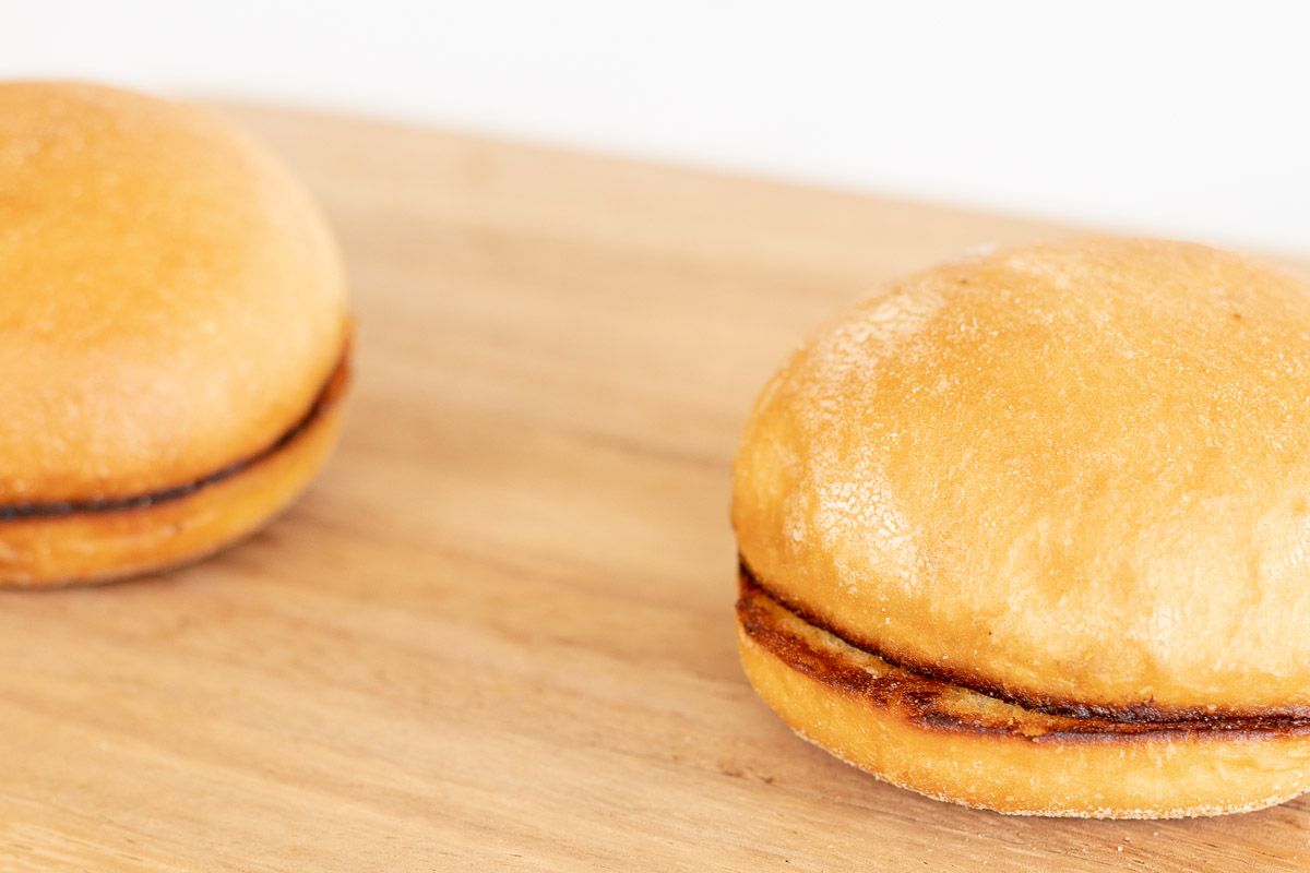 A toasted burger bun on a wooden cutting board
