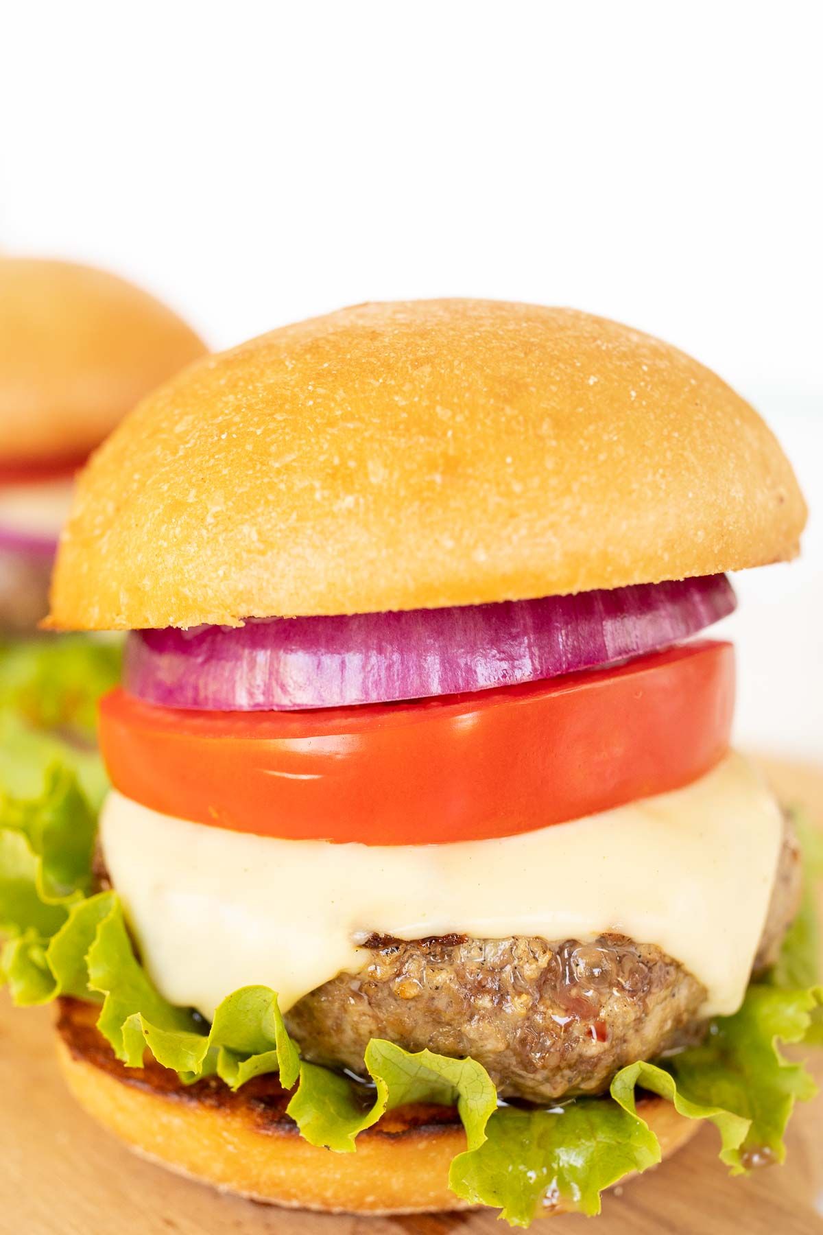 A burger stacked with toppings and a toasted burger bun.