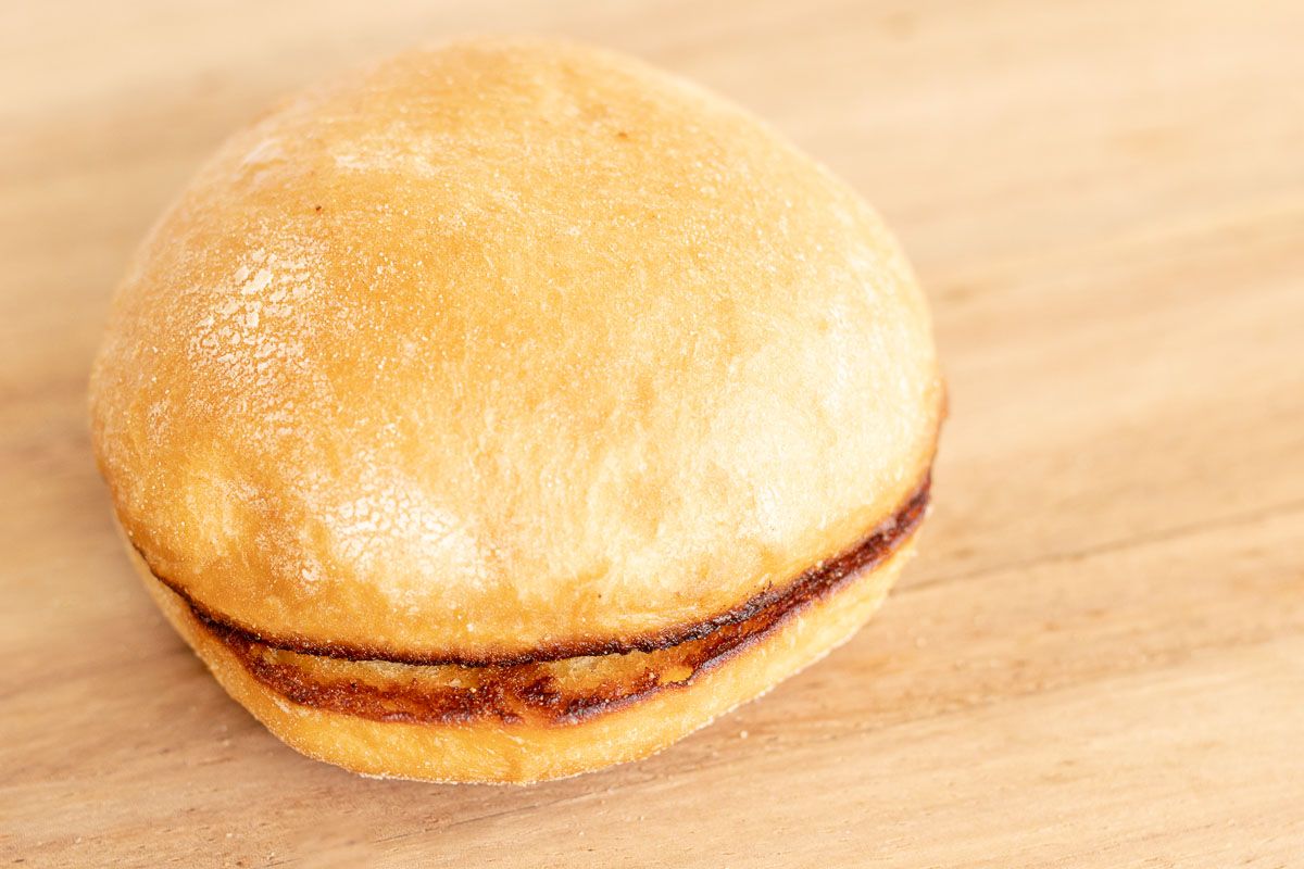 A toasted burger bun on a wooden cutting board