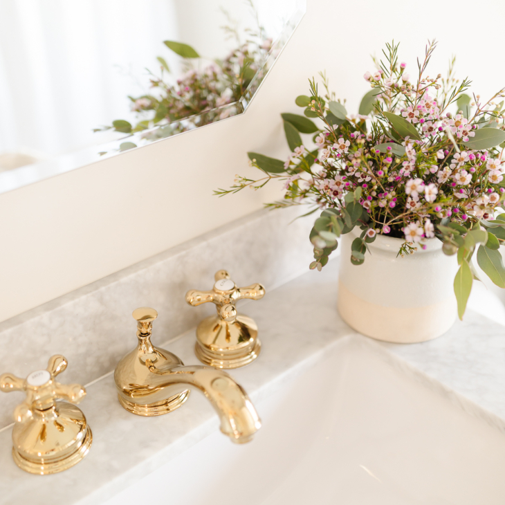 widespread brass bathroom faucet on marble sink with flowers