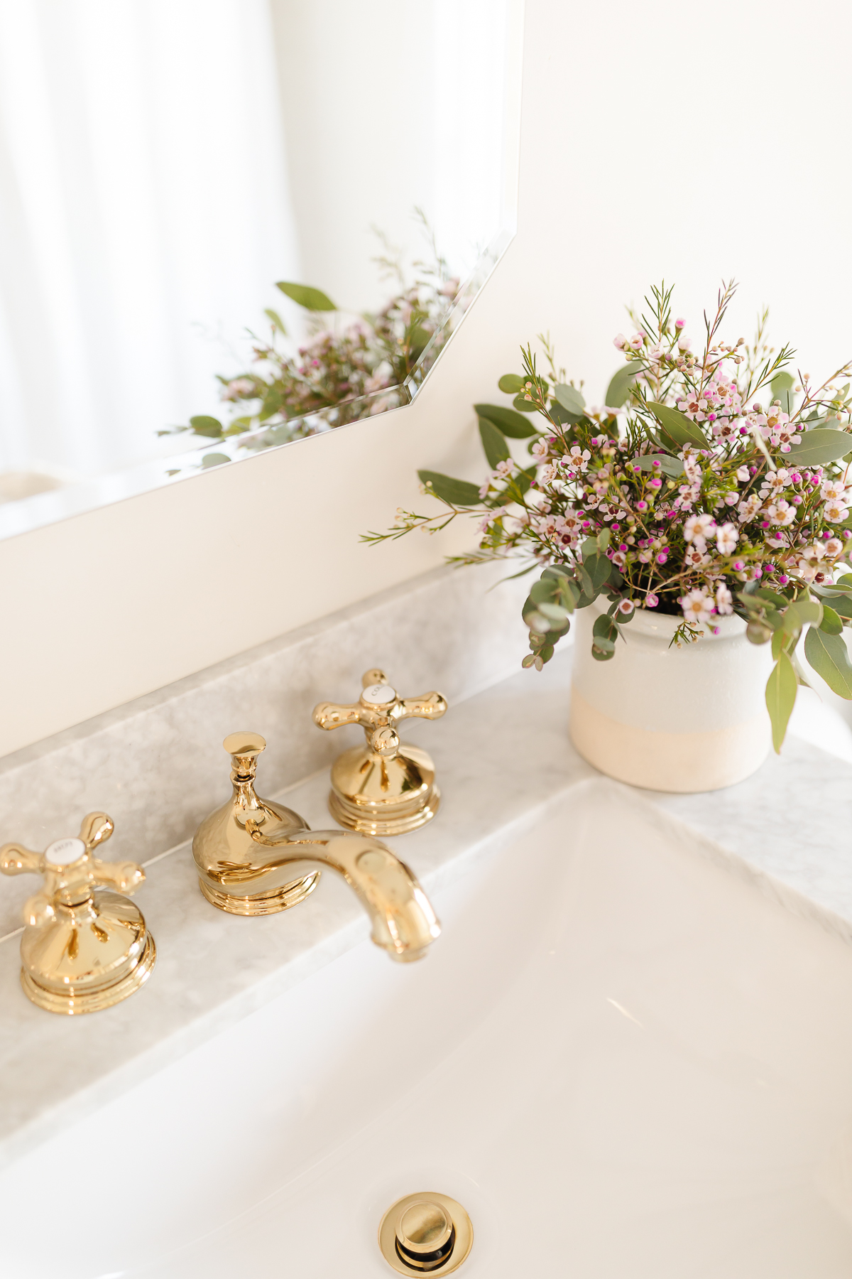 widespread brass bathroom faucet on marble sink with flowers