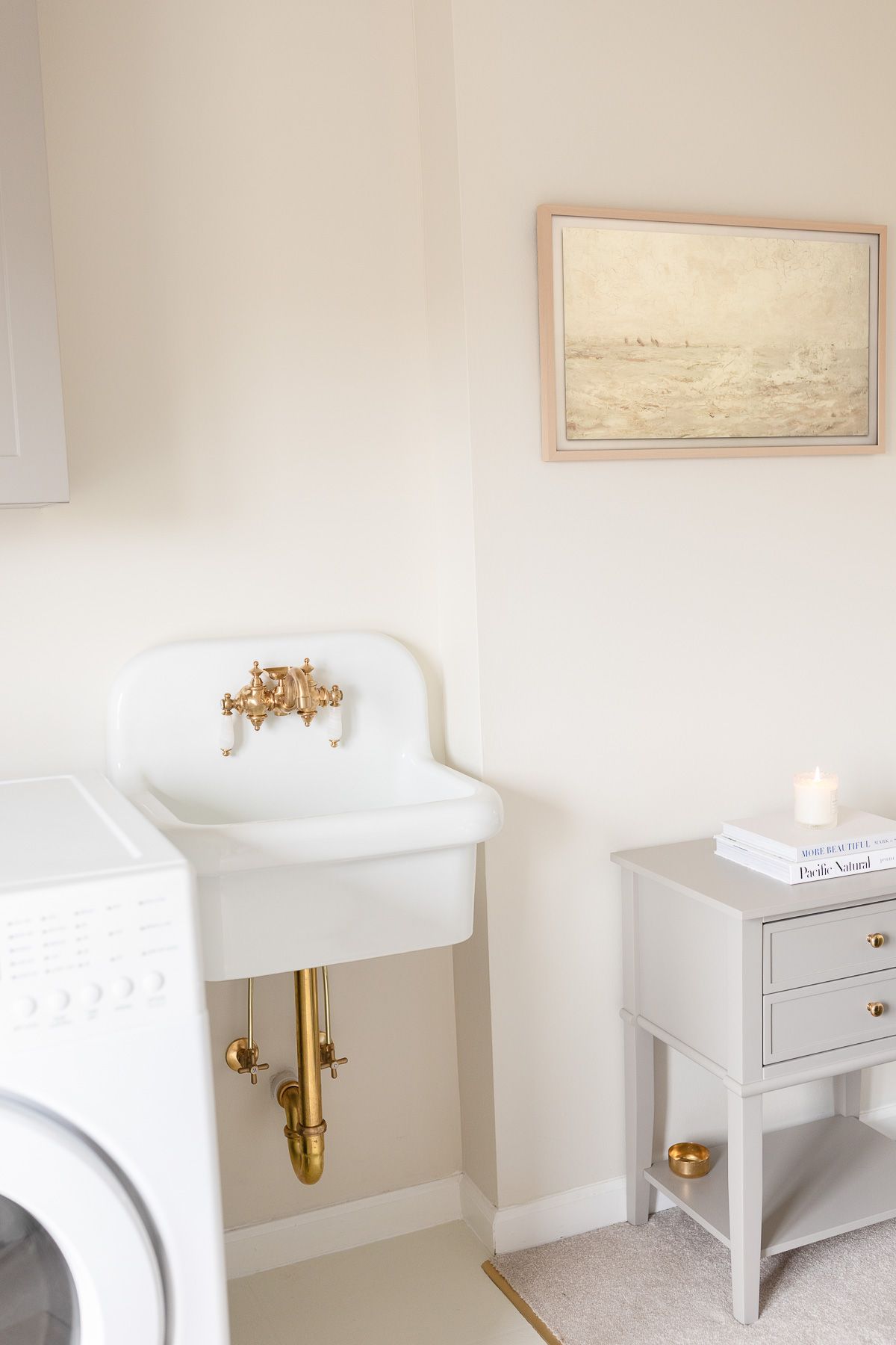 A laundry room and home gym with neutral art for the frame tv on the wall