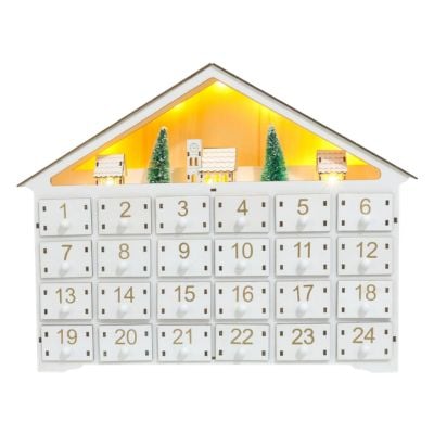 A wooden advent calendar shaped like a house, featuring 24 numbered drawers and illuminated miniature buildings on the roof.