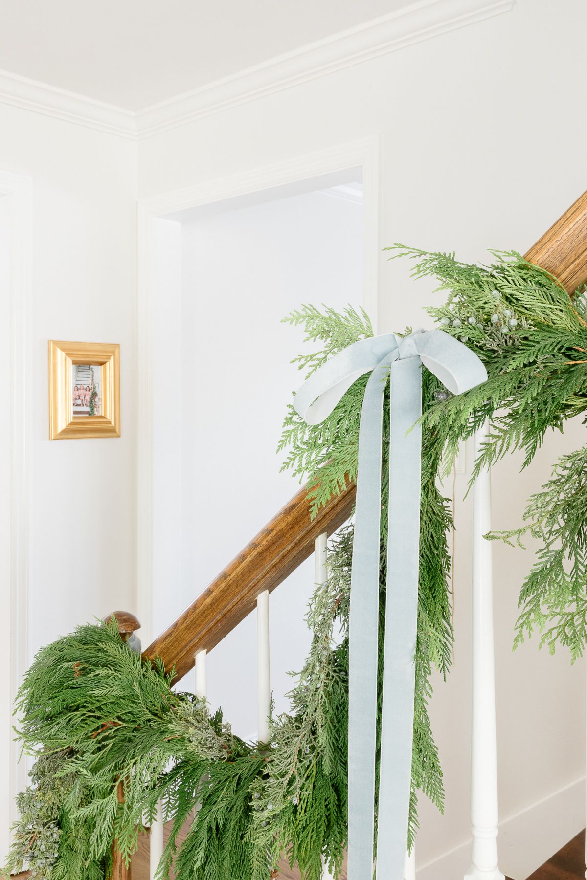 Fresh cedar garland on a staircase, tied with blue ribbon