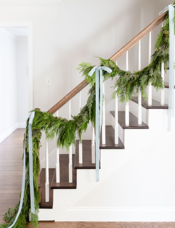 Fresh cedar garland on a staircase, tied with blue ribbon