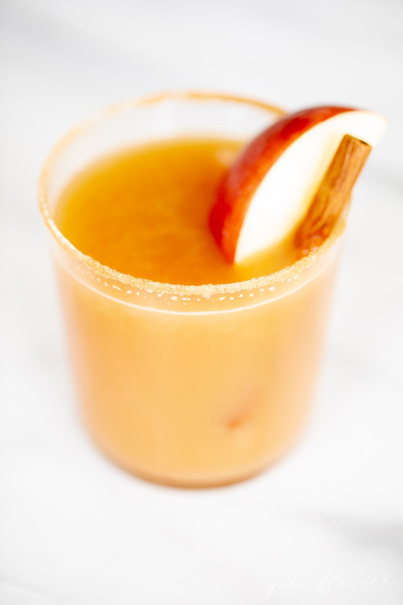 A christmas cocktail garnished with an apple slice and cinnamon stick