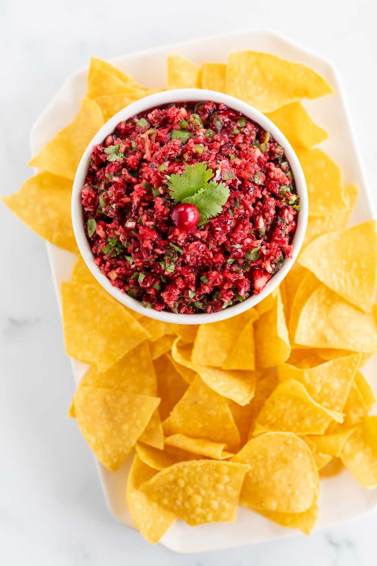 A bowl of Christmas salsa made with cranberries, surrounded by tortilla chips