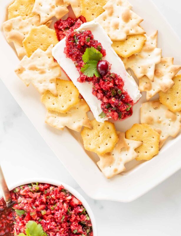 A platter of crackers surrounding cranberry salsa on a block of cream cheese