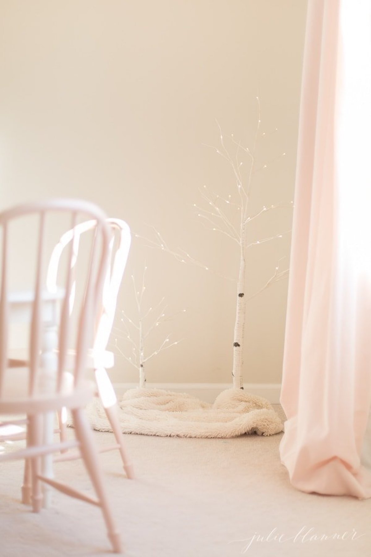 A pink and white room with a fairy light tree.