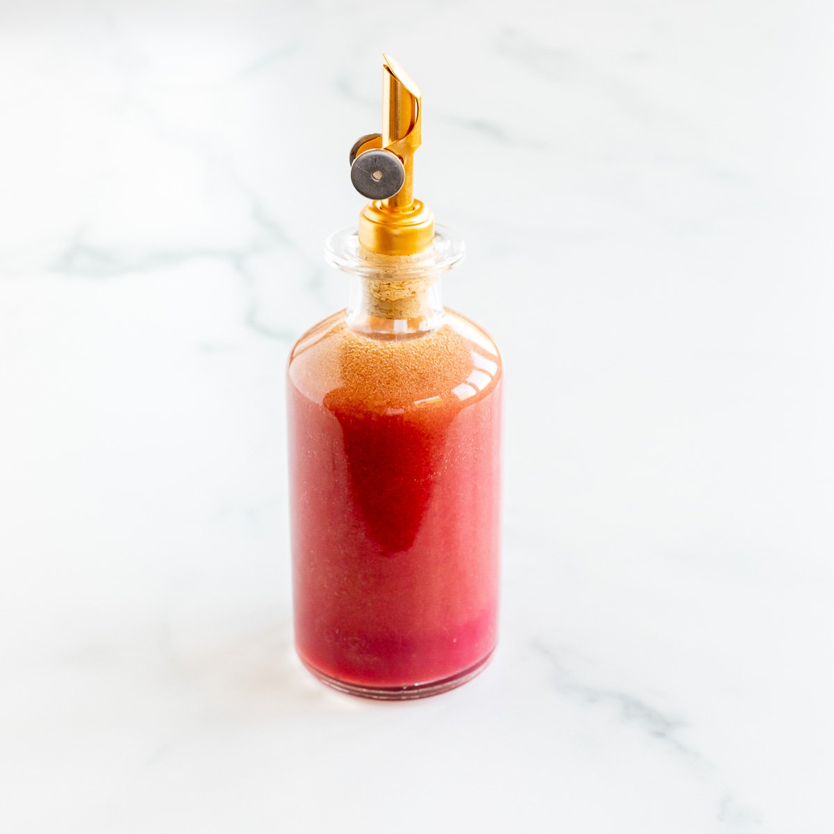 pomegranate vinaigrette in glass oil bottle with gold dispenser