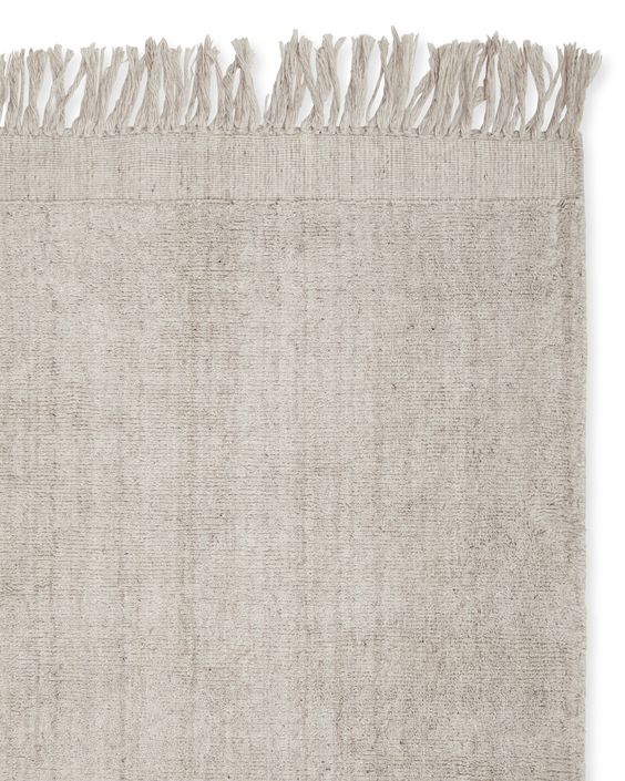 a neutral rug with fringe