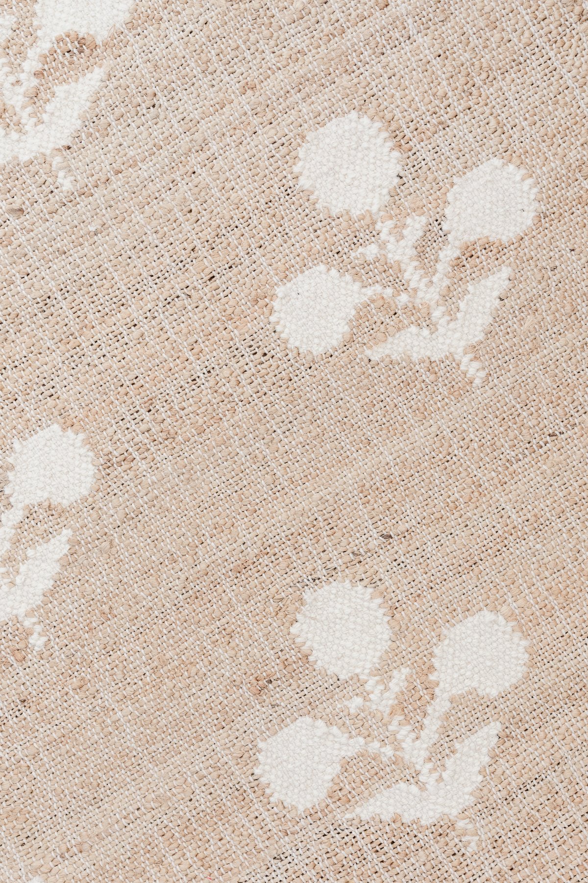 A close up of a beige fabric with white flowers on it, ideal for neutral rugs.