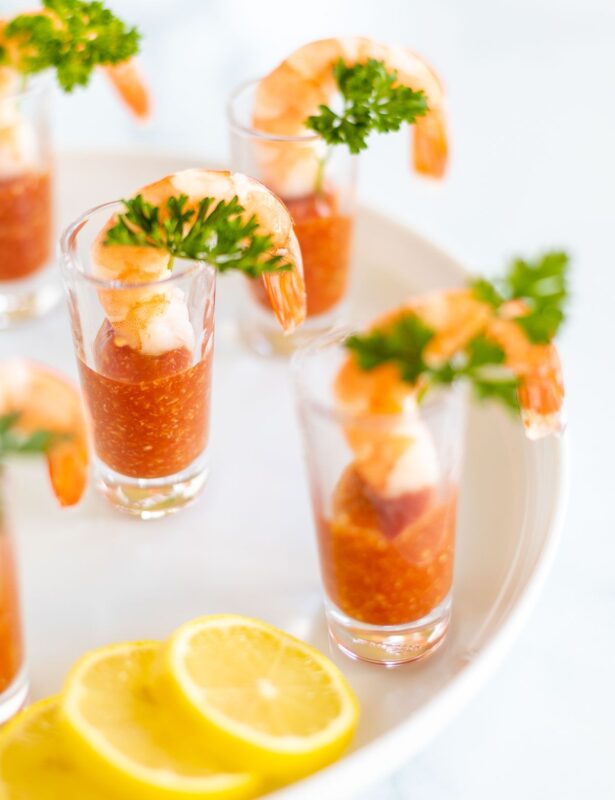 A platter of shot glasses filled with individual shrimp cocktails