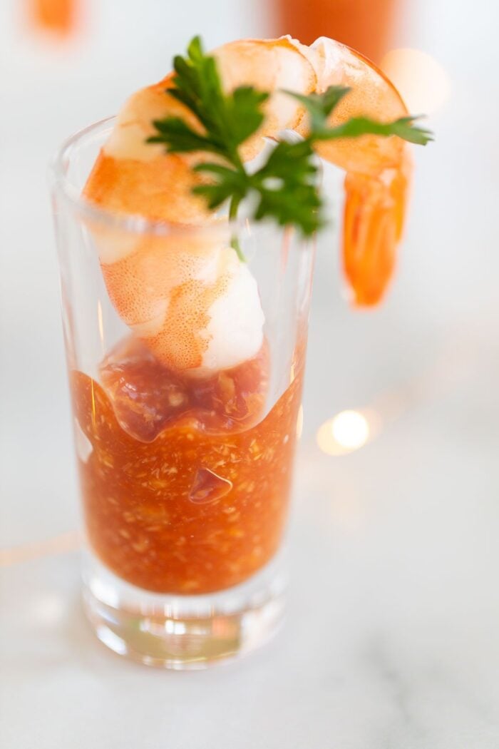 A single shrimp in a shot glass of cocktail sauce.