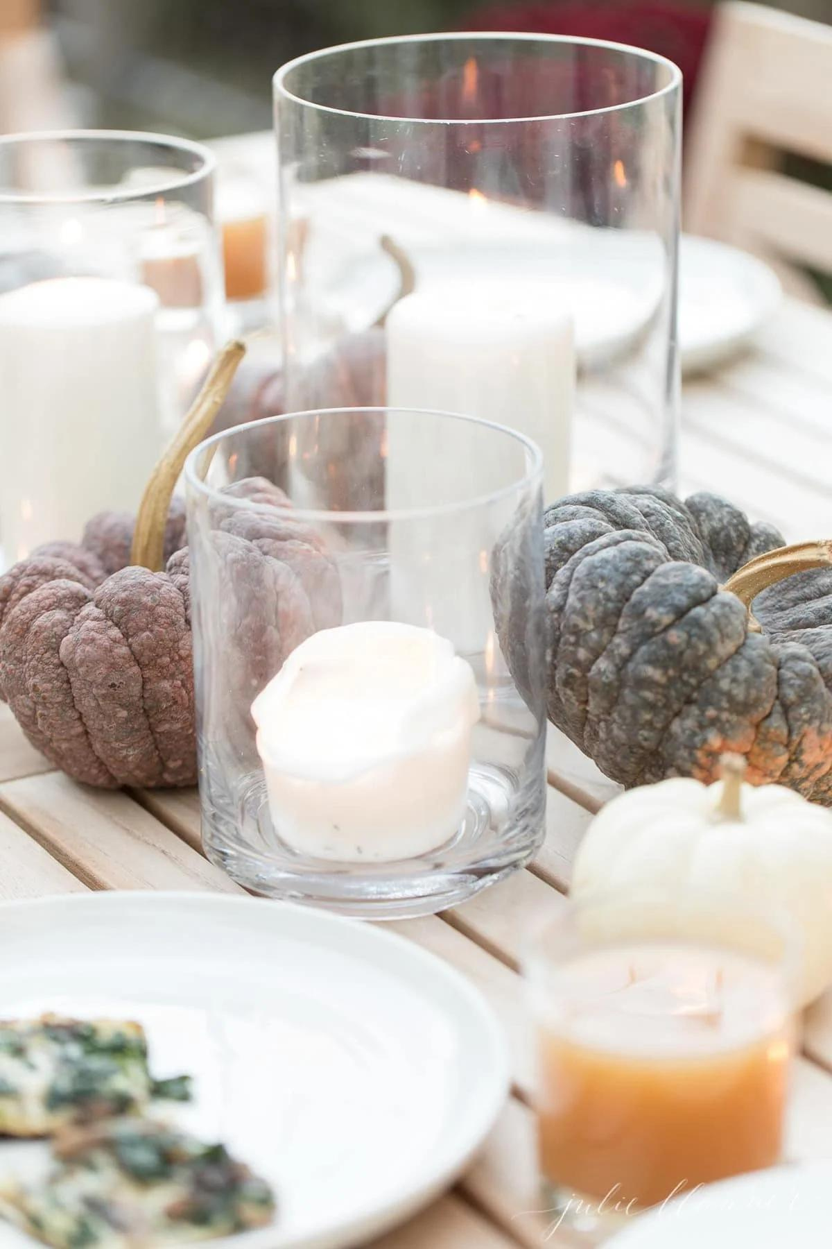 A Thanksgiving table with candles and pumpkins as centerpieces, creating a beautiful and festive decor.
