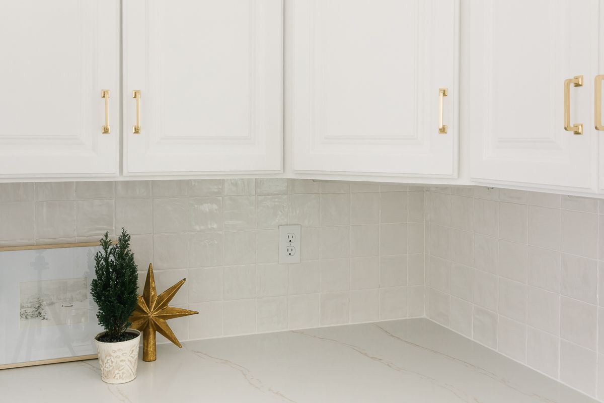 White kitchen cabinets with a white tile backsplash, with a white polyblend grout color