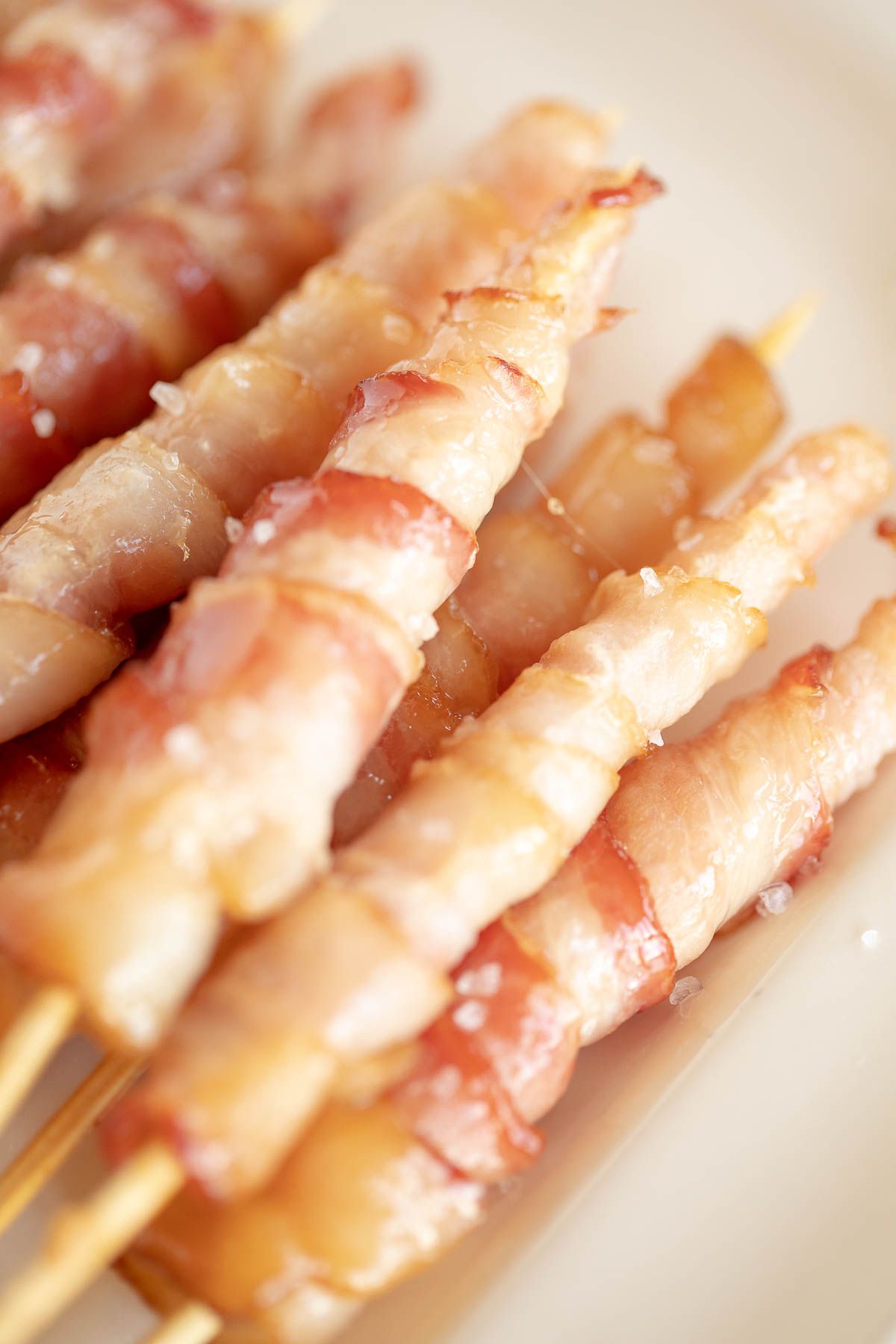 Caramelized bacon skewers on a white platter.