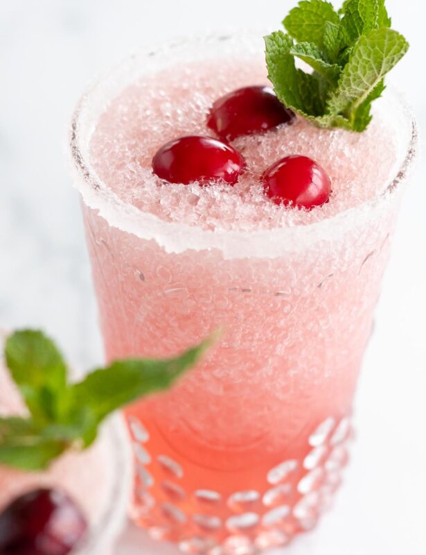 A pair of cranberry margaritas topped with fresh cranberries and mint