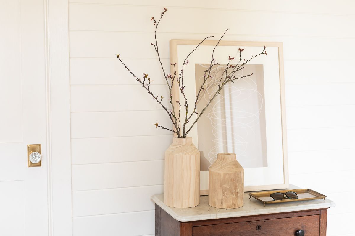 A mudroom with white walls, brick floors and a small wood cabinet. 