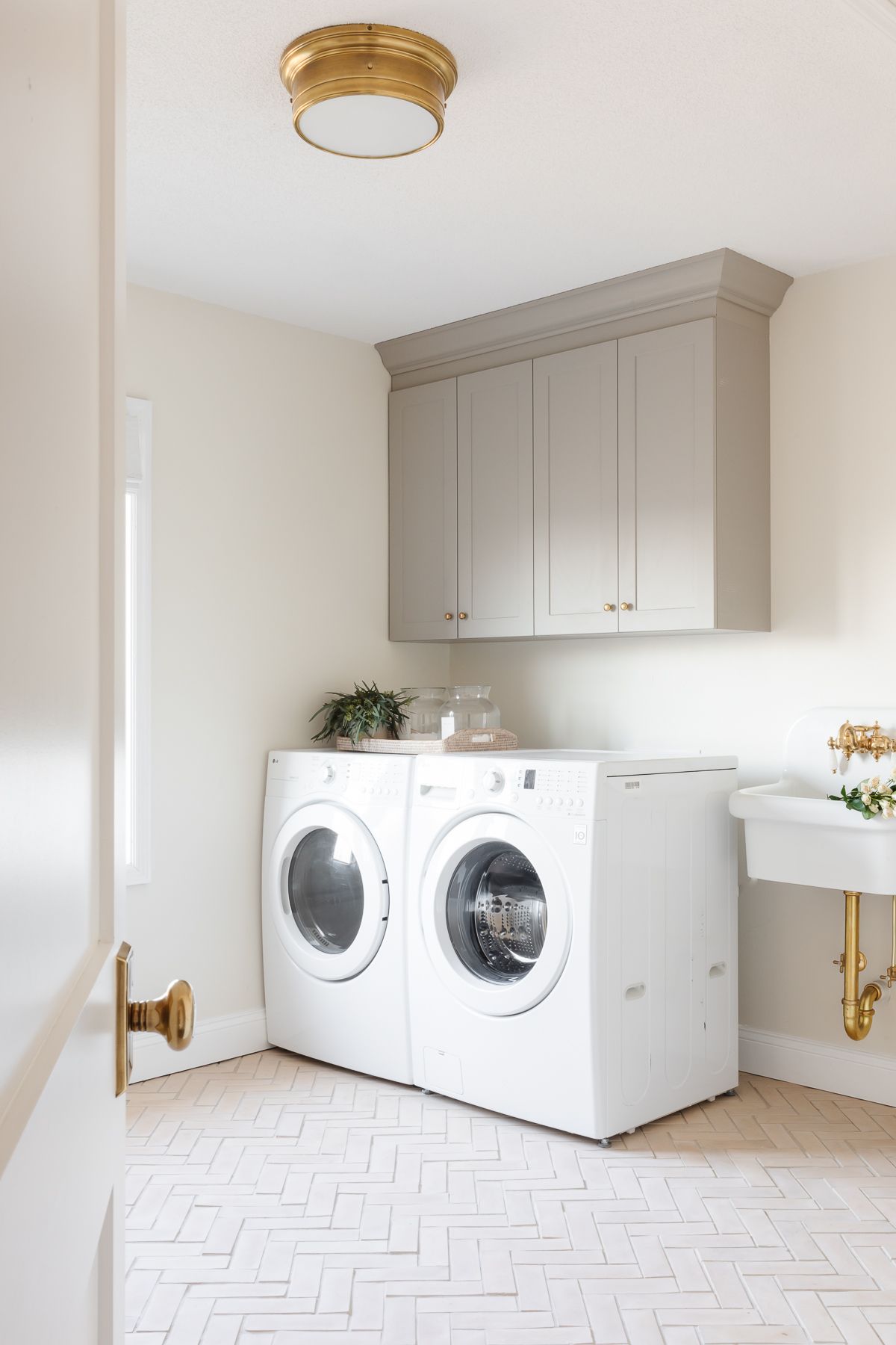 A laundry room with white washer and dryer and gray cabinets.